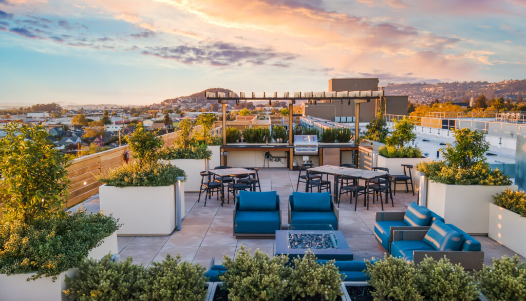 Roof top terrace with green landscaping in planters and various blue themed seating areas